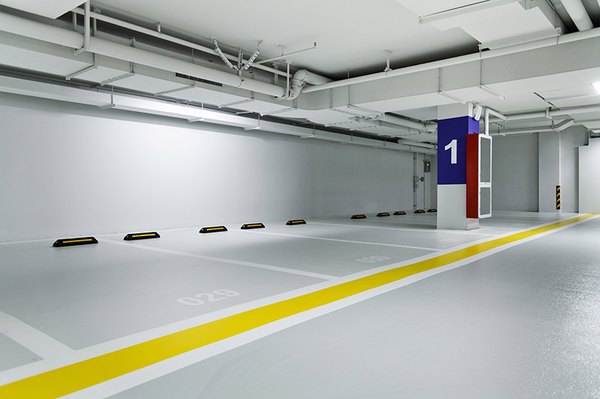 Ein moderner Tiefgaragenkomplex mit neuer Bodenbeschichtung. Zu sehen sind einige freistehende Stellplätze.